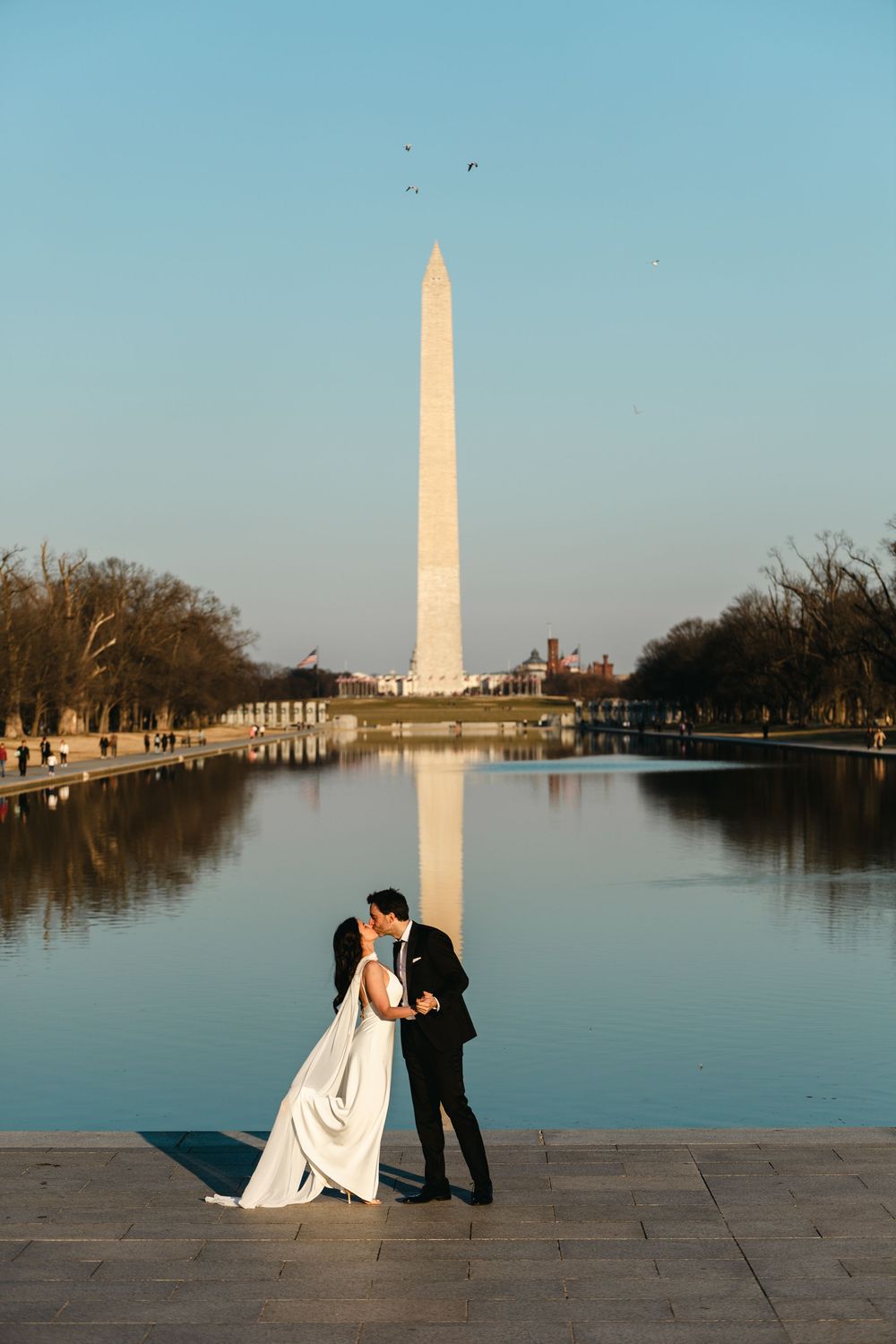 Bride and groom kissing in front of the Washington Monument and Reflecting Pool on their wedding day.