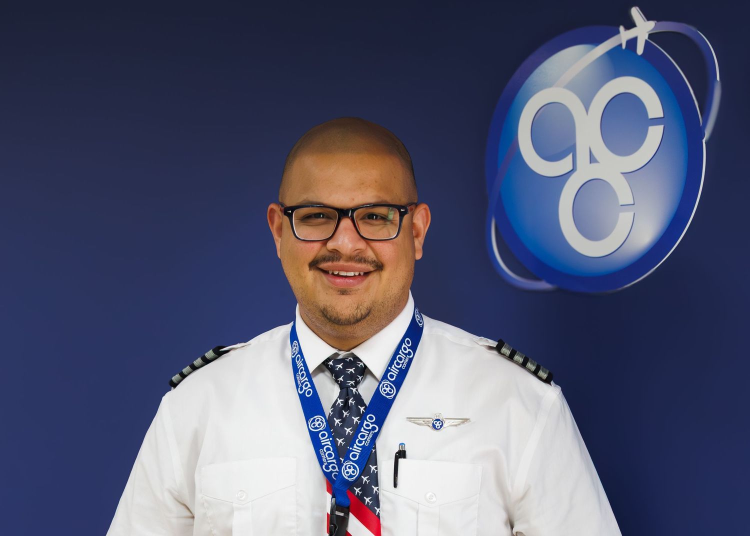 Professional man in pilot uniform smiling in front of aviation company logo.