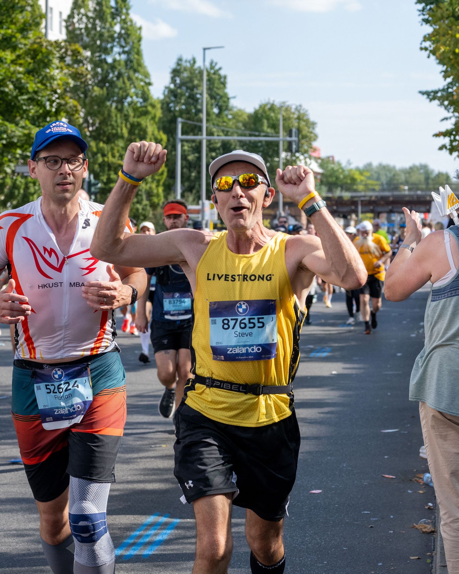 Runner wearing Livestrong jersey, celebrates with raised fists at BMW Berlin Marathon race.