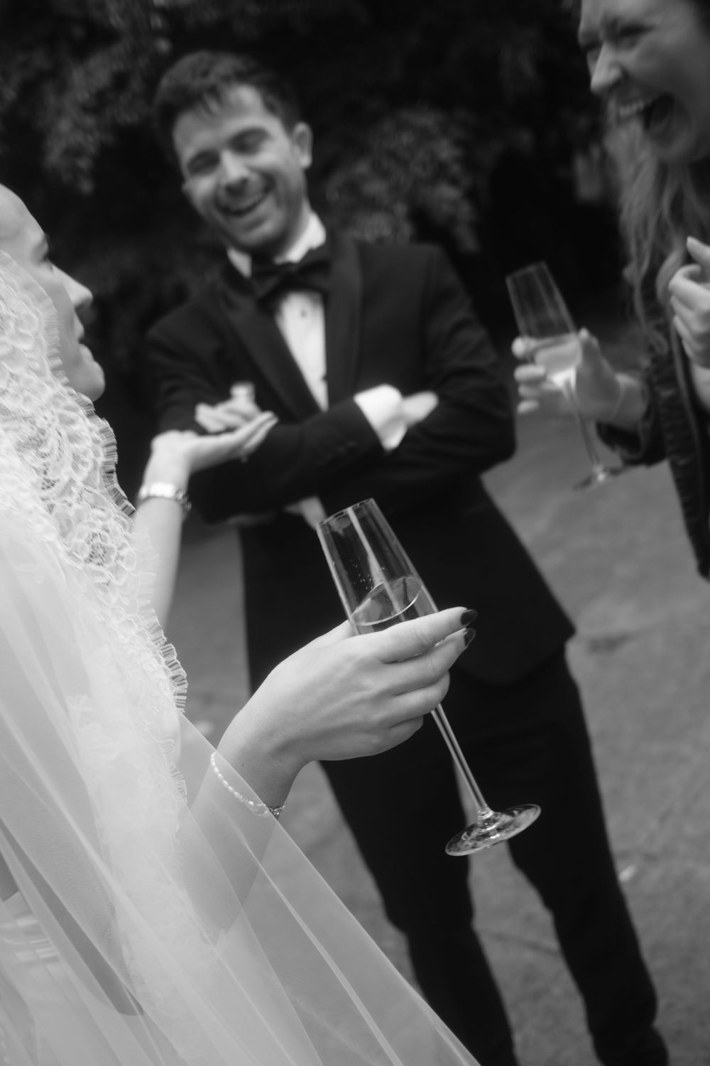 Black and white wedding photo of bride holding champagne flute with smiling groom in tuxedo at St Mary Redcliffe Church, Bristol Wedding