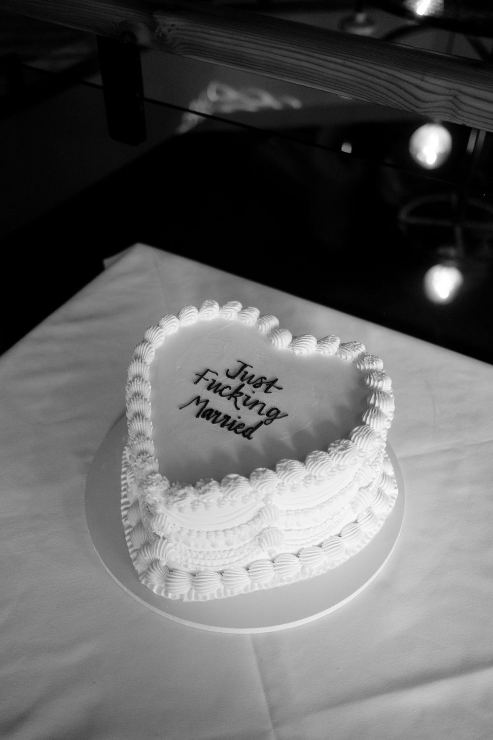 Heart-shaped wedding cake with Just Fucking Married inscription in black and white photography at Pasture Bristol Wedding