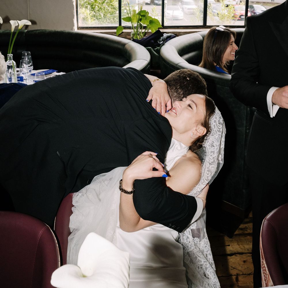 Bride in white lace gown shares romantic hug with groom in black suit at wedding reception at Pasture Resturant Bristol