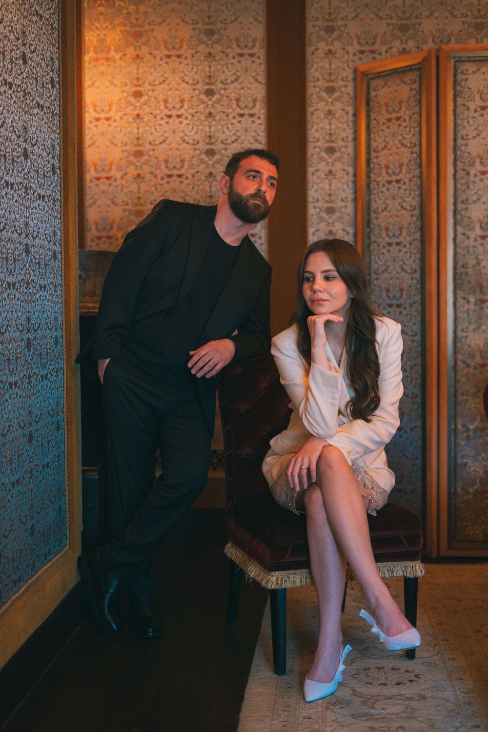 Photo d'un couple ou l'homme est debout accouder à une chaise et la famme assise