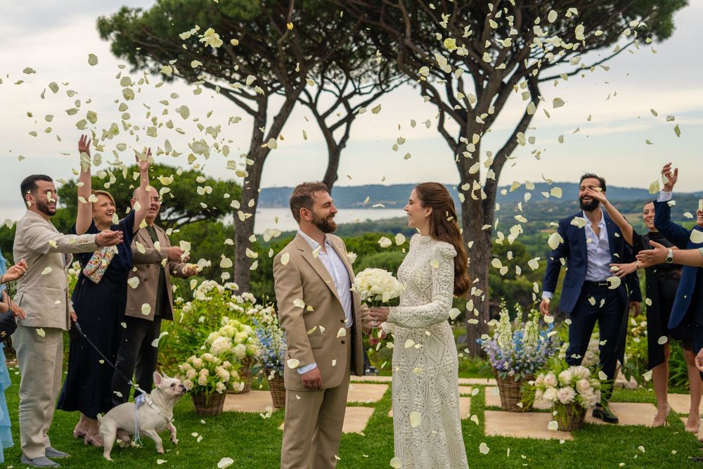 Photo des mariées qui recoivent des pétales de fleur des invités