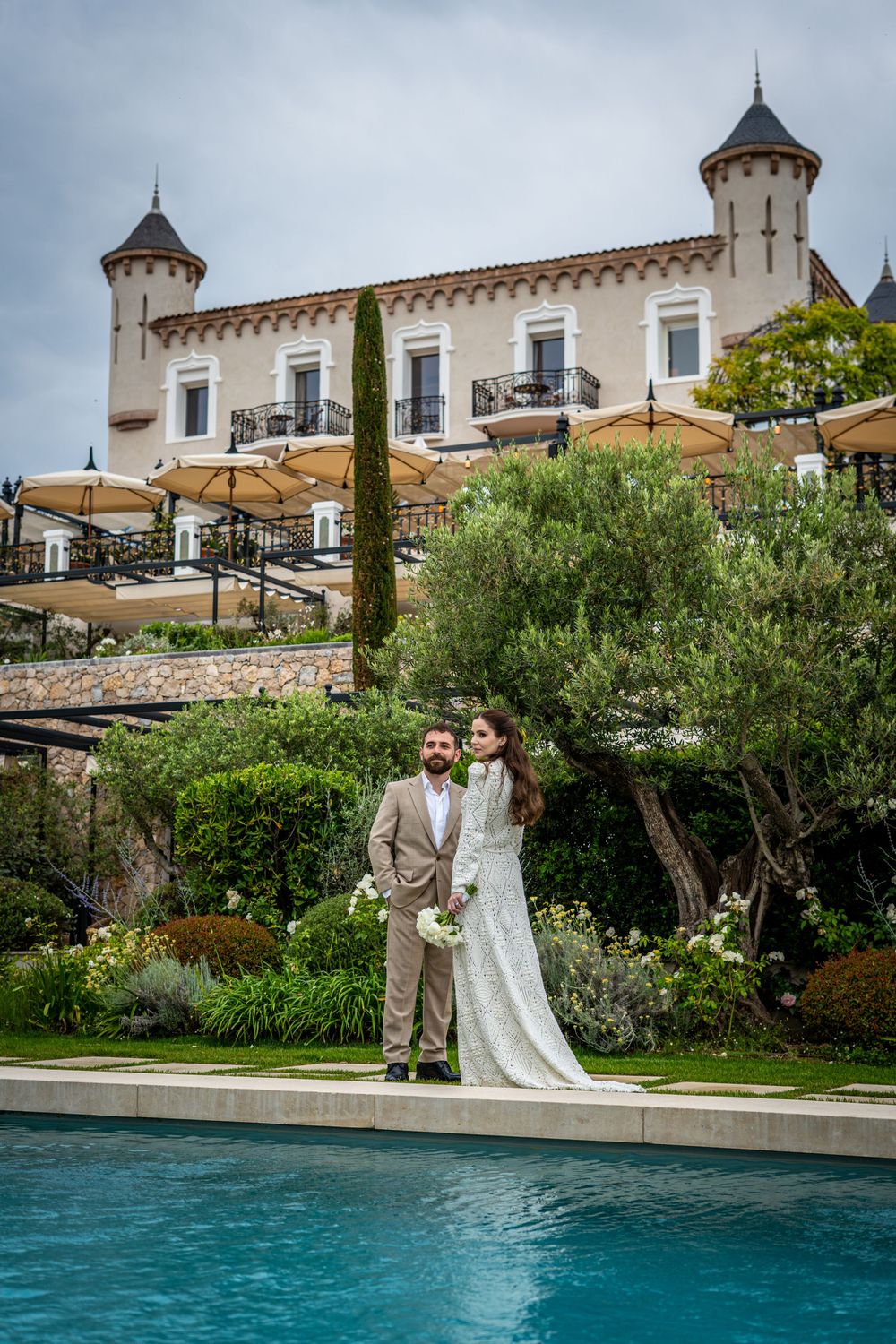 Photo des mariées devant la piscine avec le chateau en fond