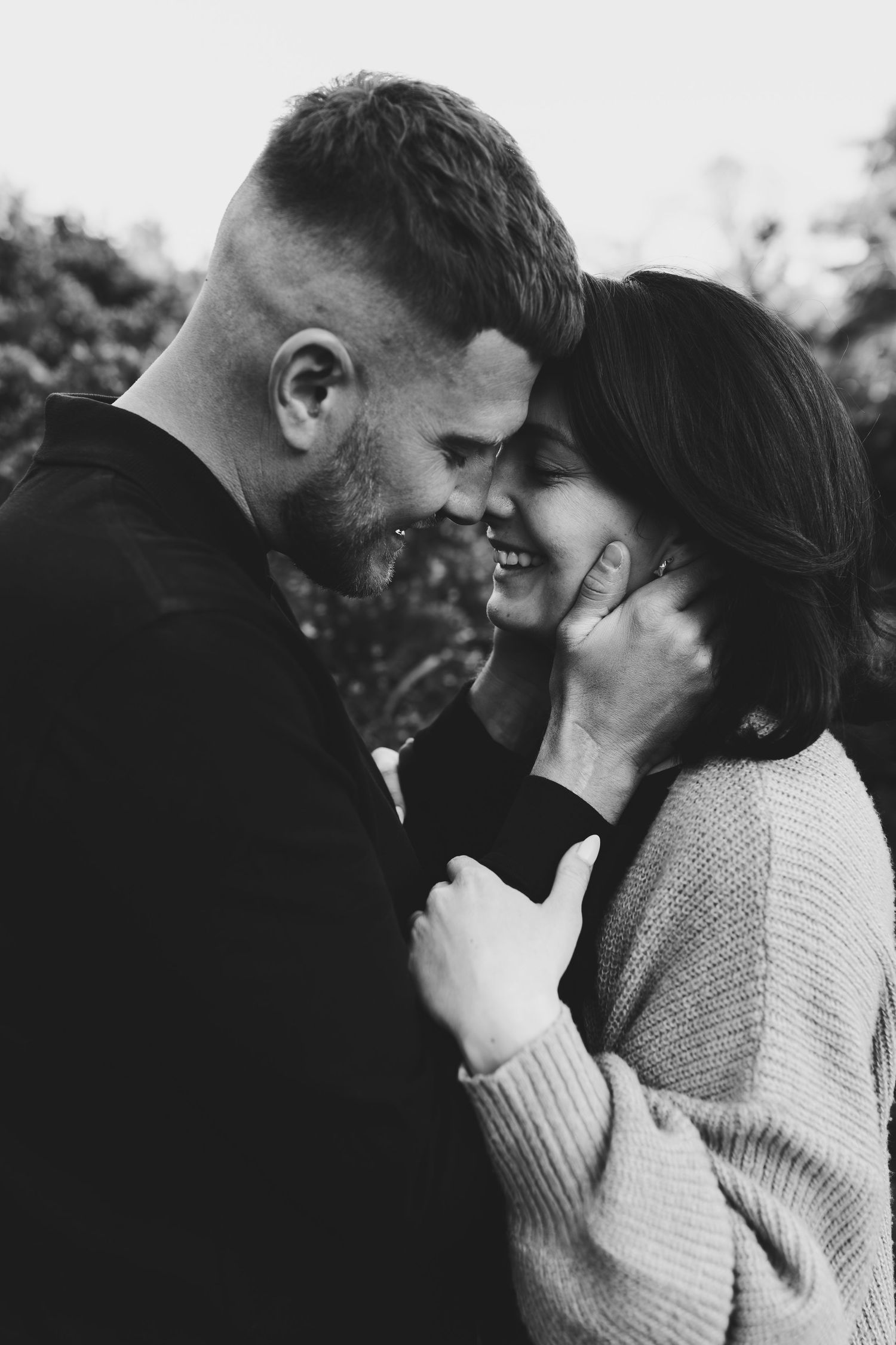 The wedding couple posing together in a field during golden hour, embracing and smiling.