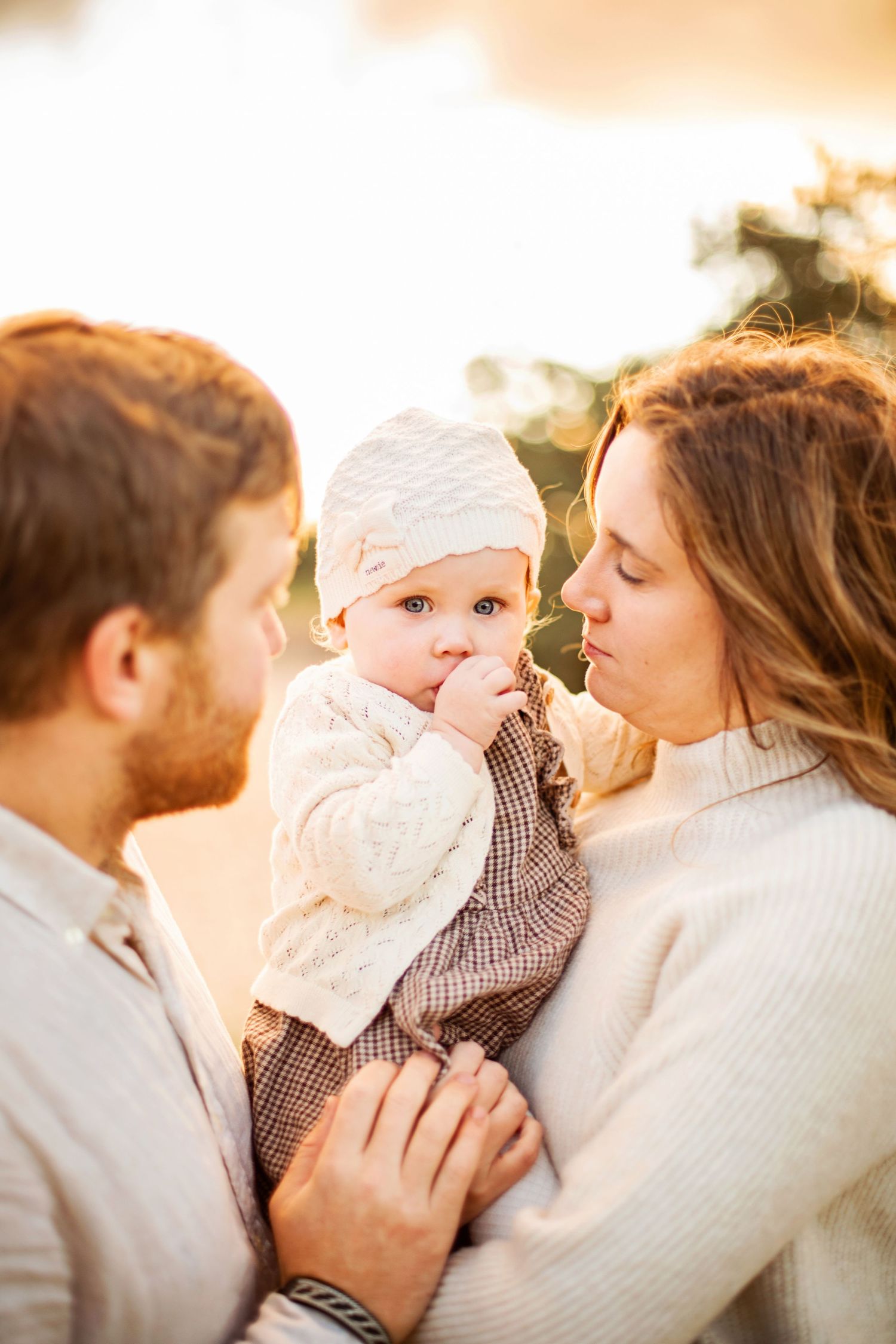 A tender moment between parent and child sitting outdoors in a summer meadow at golden hour.