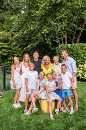 Large family group portrait smiling together in a lush green backyard garden during summer.