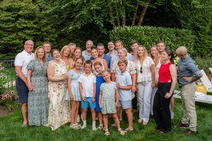 Large family group smiling together outdoors in a lush green garden during a summer gathering.