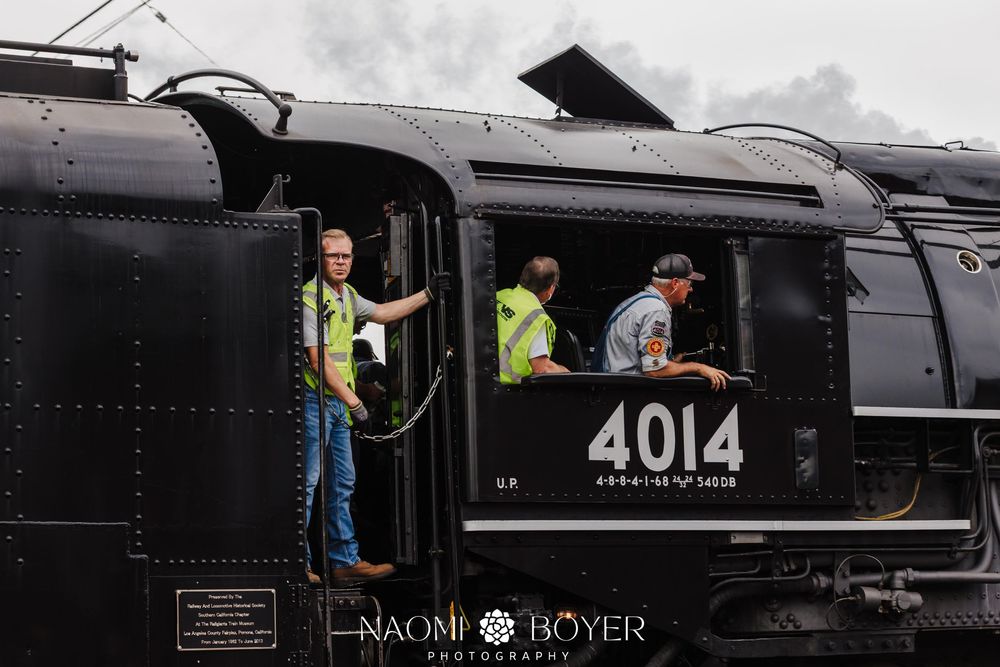 Crew members work on Union Pacific steam locomotive 4014 Big Boy, with workers in safety vests visible in the cab.