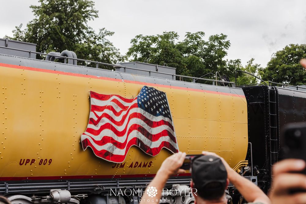 A large American flag emblem displayed on the yellow side of a Union Pacific steam locomotive at a public event.
