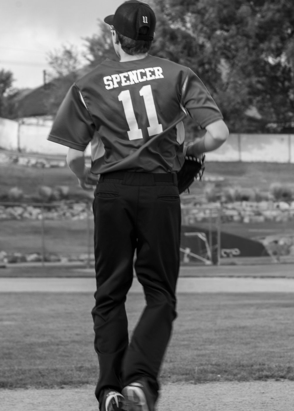 Black and white photo of baseball player Spencer wearing jersey number 11, standing on field viewed from behind.