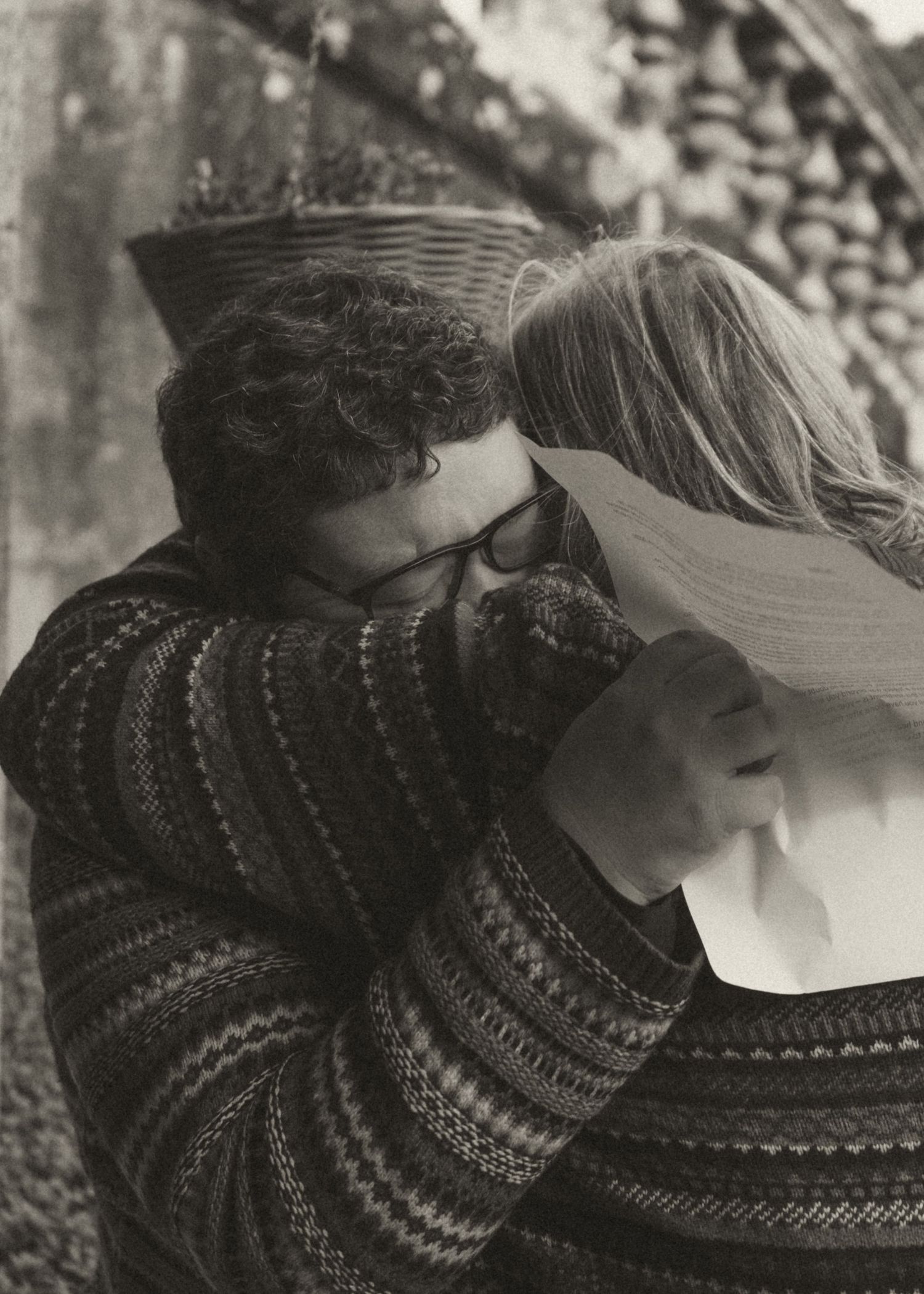Emotional black and white photograph of a couple embracing during their wedding vows, with handwritten vow papers still in hand
