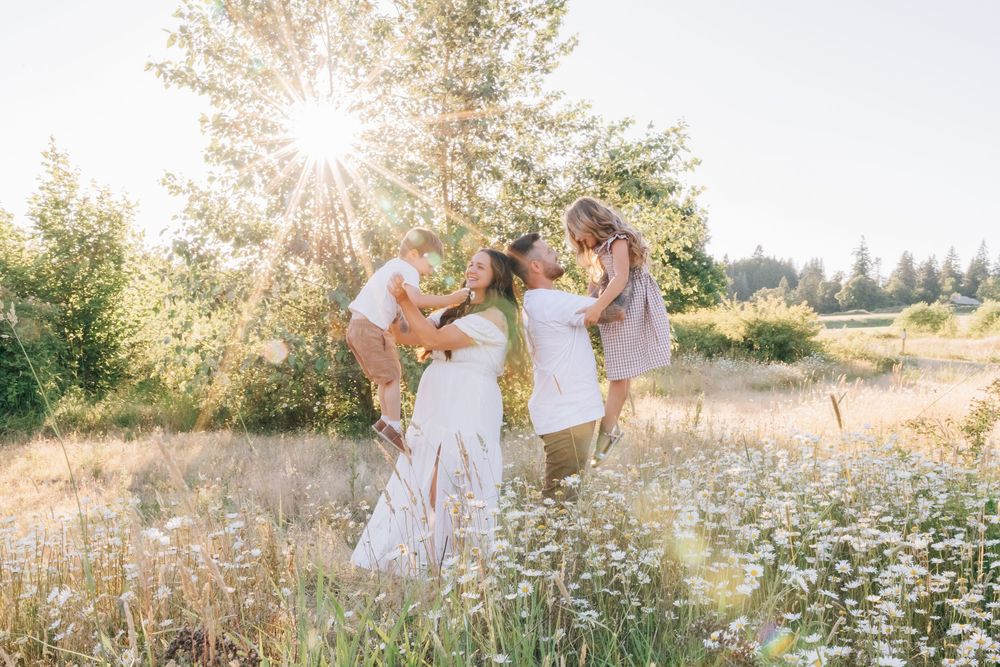 A mother kisses her children in a sunlit wildflower field on a warm summer day.