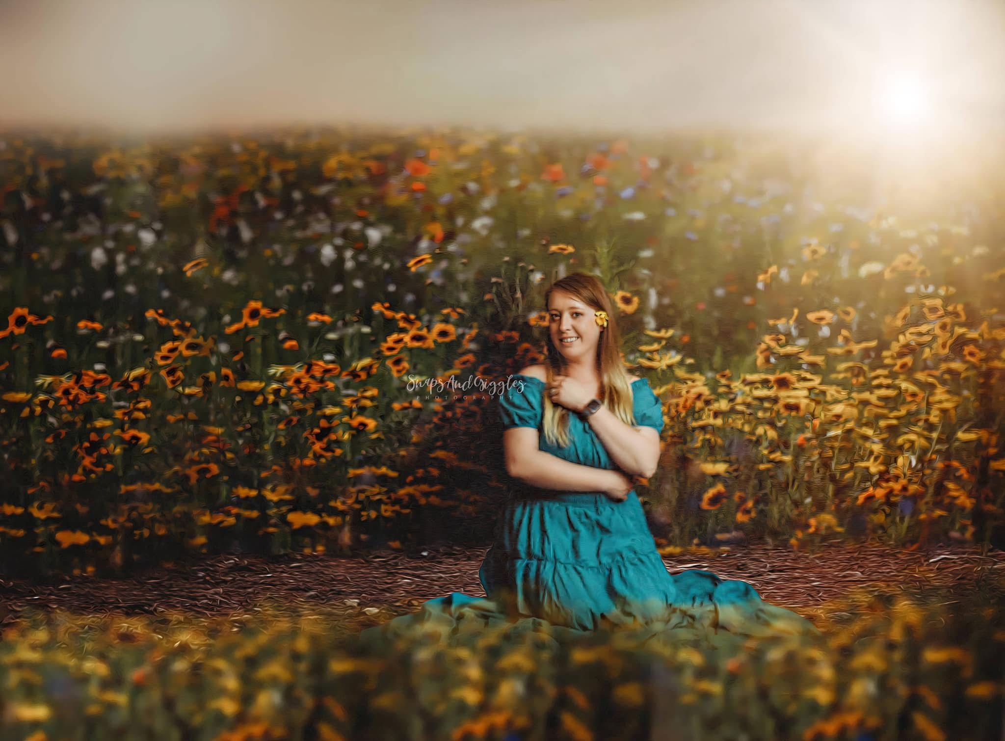A young woman in a teal dress sits gracefully in a vibrant sunflower field bathed in warm golden light.