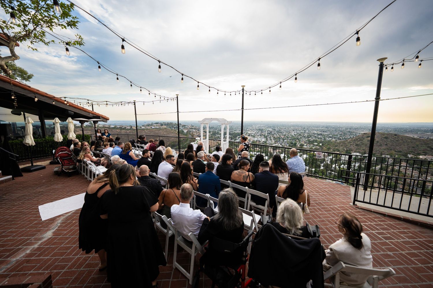 Outdoor wedding ceremony with seated guests and string lights at Melissa and Sean's wedding.