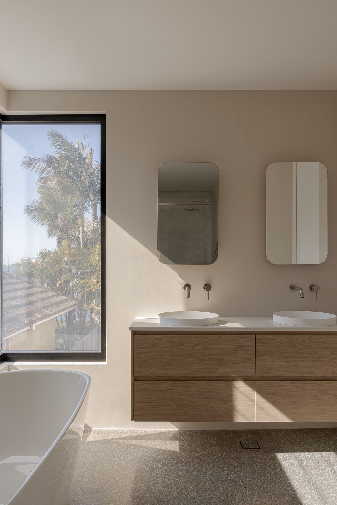 Bathroom with a timber vanity, round mirror and soft natural light, interior photography of a coastal home in Shoalhaven NSW.