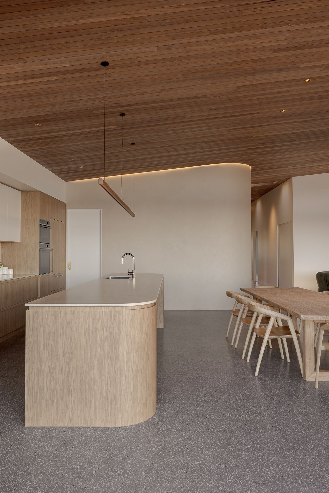 Oak kitchen with a curved island bench and timber ceiling in a contemporary coastal home in Shoalhaven.
