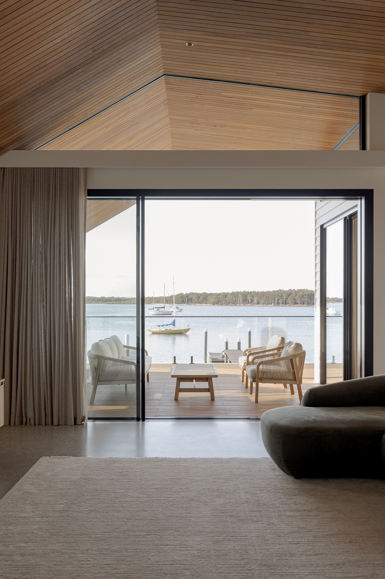 Living room opening through large sliding doors to river views, interior photography of a new home in Shoalhaven NSW.