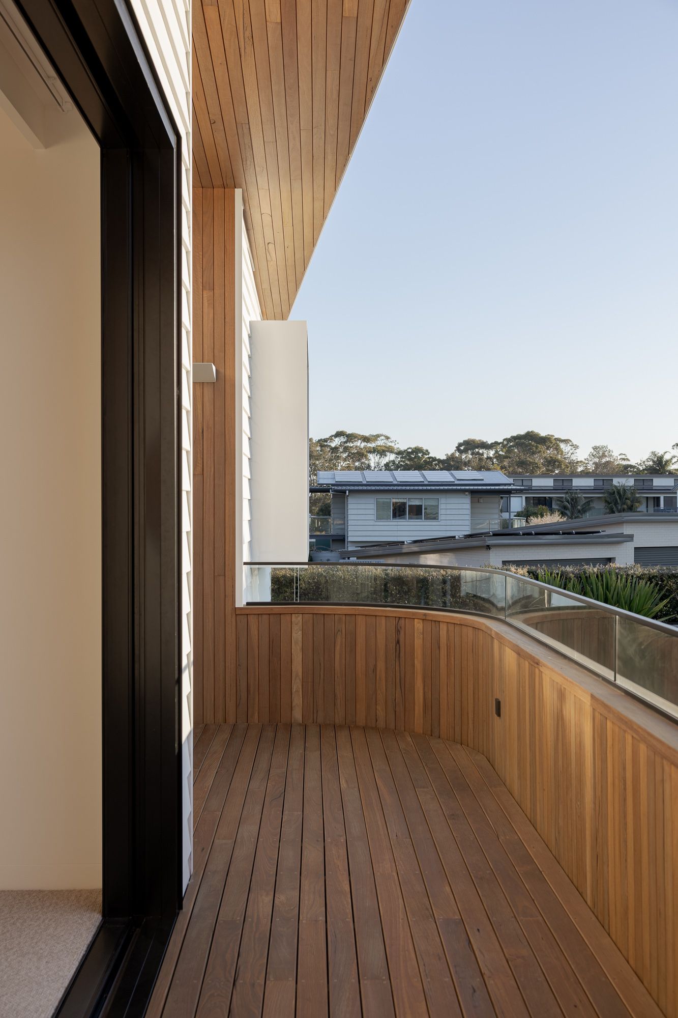 Balcony with timber decking and timber-lined walls looking out to the river at a new home on the NSW South Coast.
