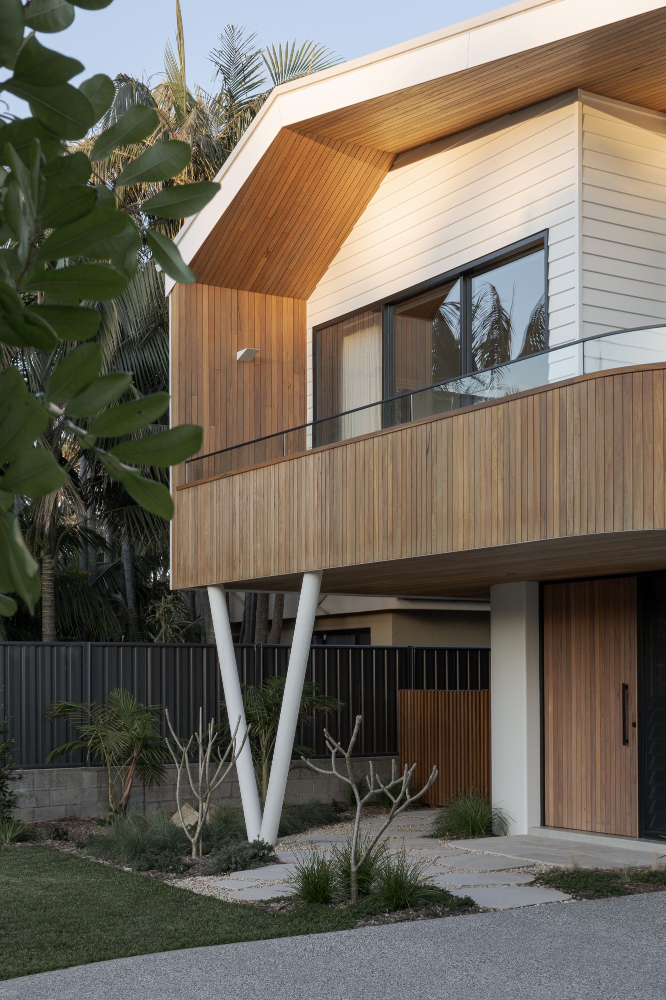 Front facade of a new architectural build on the NSW South Coast, featuring a raked roof, timber cladding and angled columns.