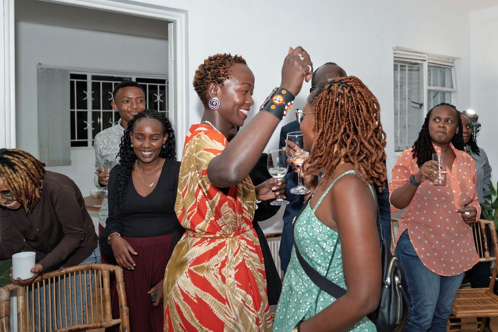 Women dancing and celebrating at an indoor party with guests in the background.