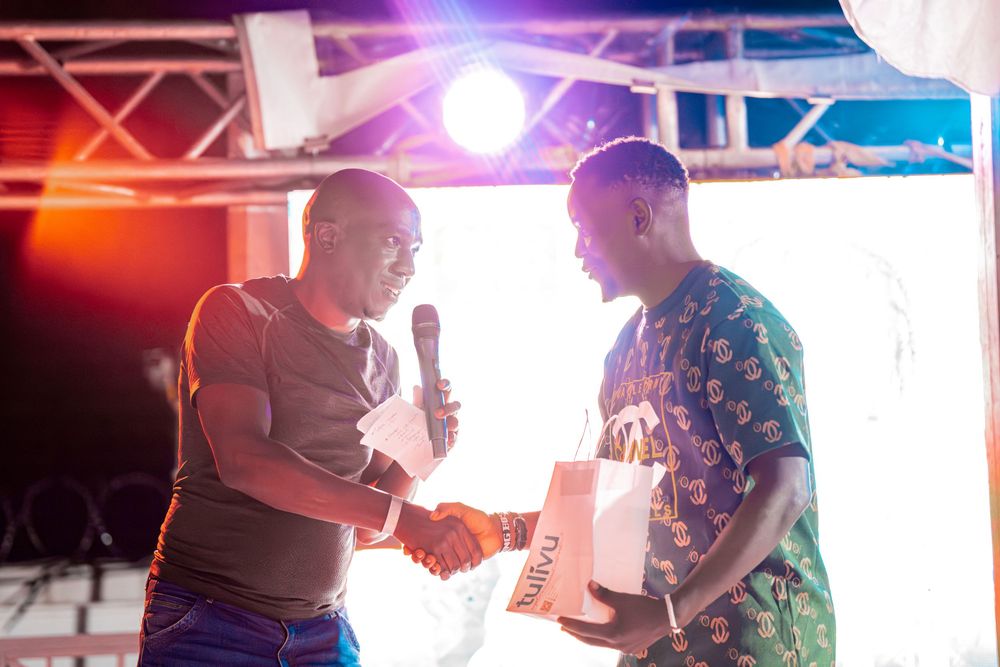 Two men shaking hands on stage under bright lights during an awards or event ceremony.