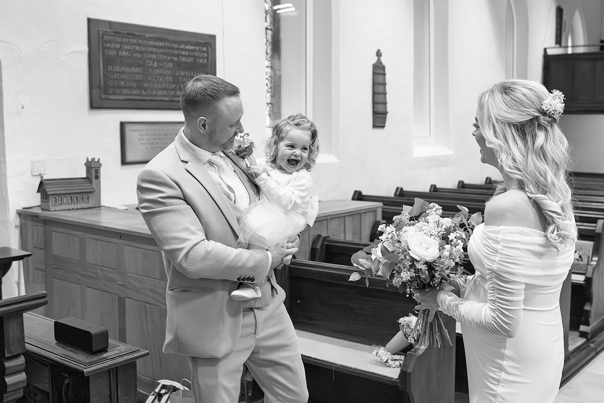 Wedding photo of groom holding a baby when bride sees the groom for the first time during their elopement wedding in the Lake District