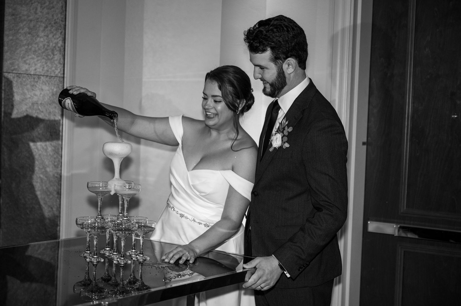 A black and white photo of a bride and groom dancing together during their first dance at a wedding reception.