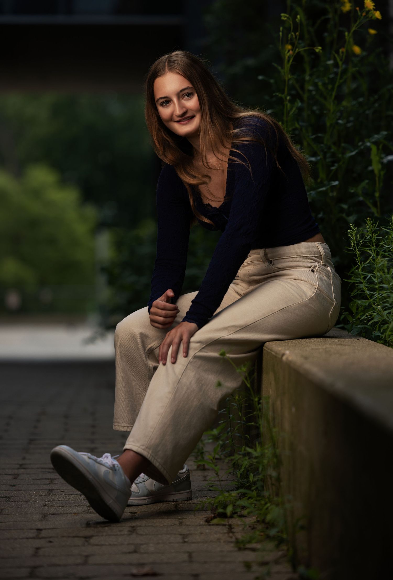 Senior girl sitting outdoors in an urban setting during her portrait session