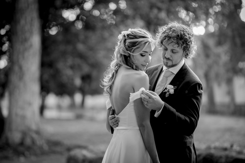 Bride and groom share an intimate moment outdoors in black and white wedding photo.