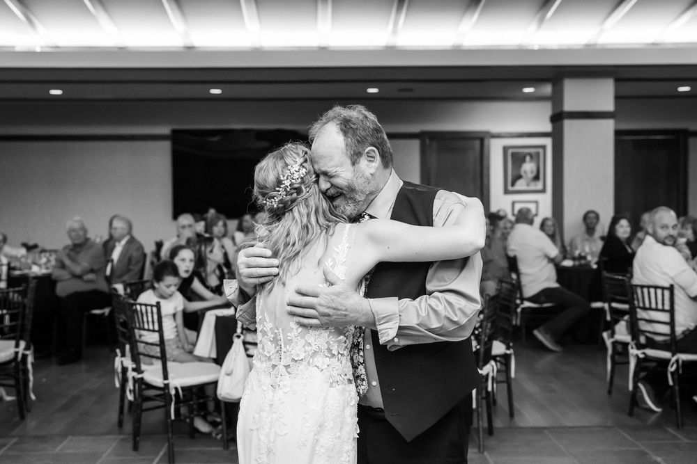 Black and white photo of bride and groom sharing emotional first dance embrace at wedding reception.