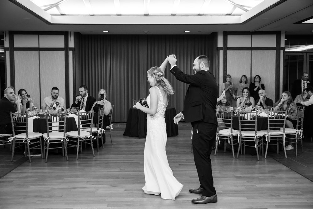 Bride and groom share first dance at elegant wedding reception in black and white photo.