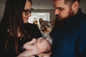 A peaceful family moment at home with a small Yorkshire Terrier and newborn baby.