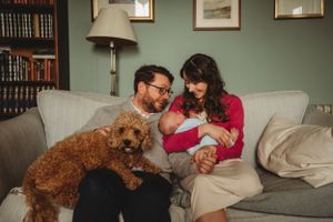 A goldendoodle dog joins family on cozy green couch in a room with vintage decor.