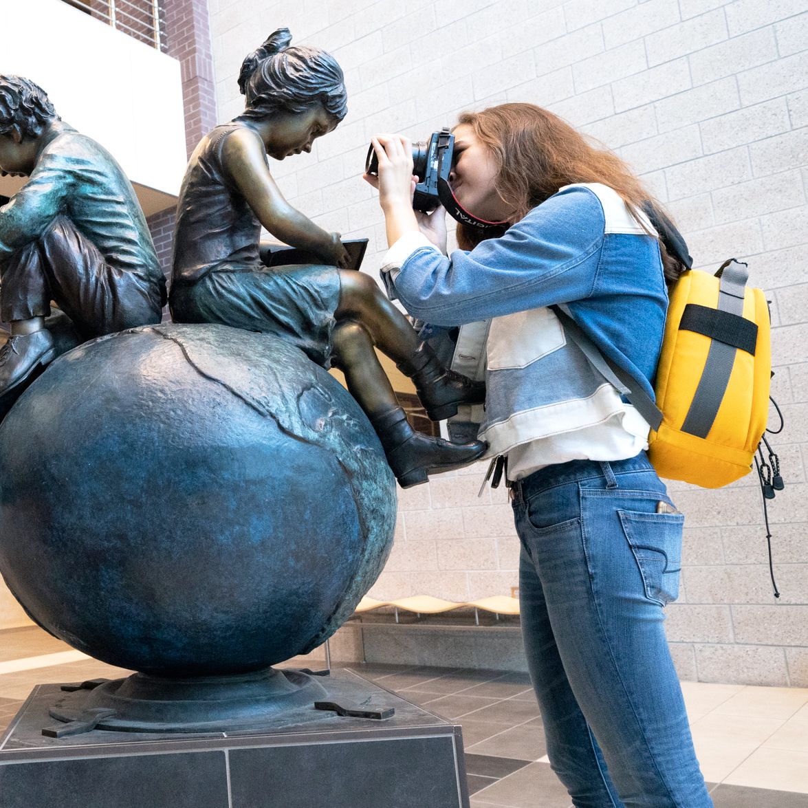 High school girl with backpack photographs a statue unclose during a class by Arkansas educator, Alex Kent