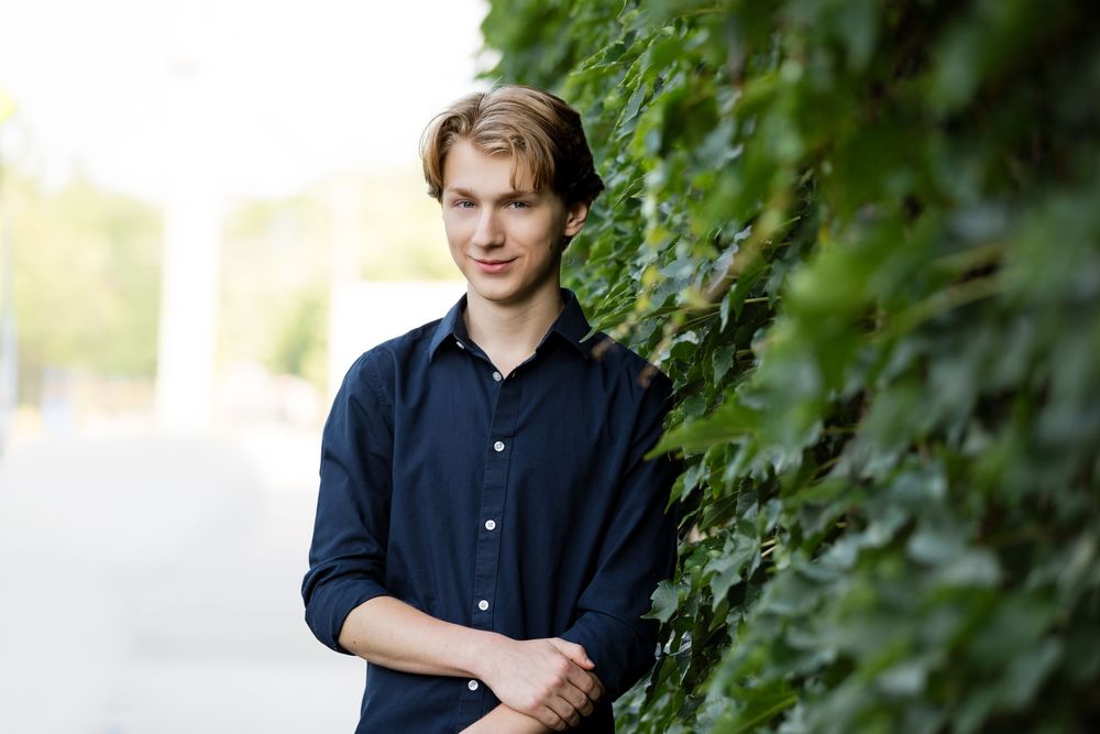 High school senior guy pictures in Howell, MI; boy standing against brick and ivy wall, by South Lyon, Michigan photographer