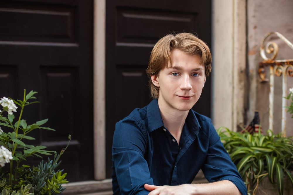 High school senior boy portrait in Howell, MI; headshot of boy sitting on Alley District steps, by Brighton, Michigan photographer