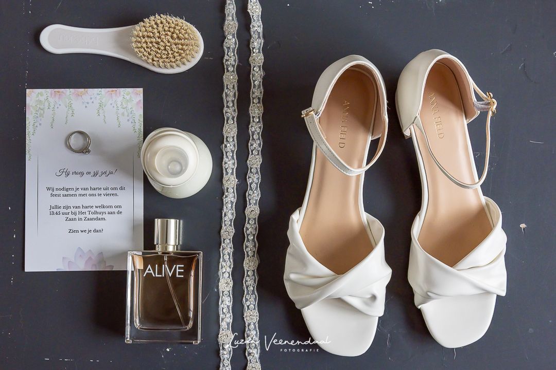 Flatlay op tafeltje met de trouwkaart, trouwring, trouwschoenen, parfum maar ook moet de babyborstel en de babyfles op tafel erbij