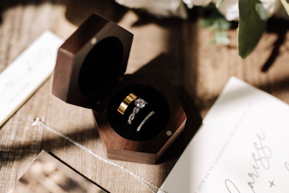 Two wedding rings displayed in an open hexagonal wooden ring box on a wooden surface.