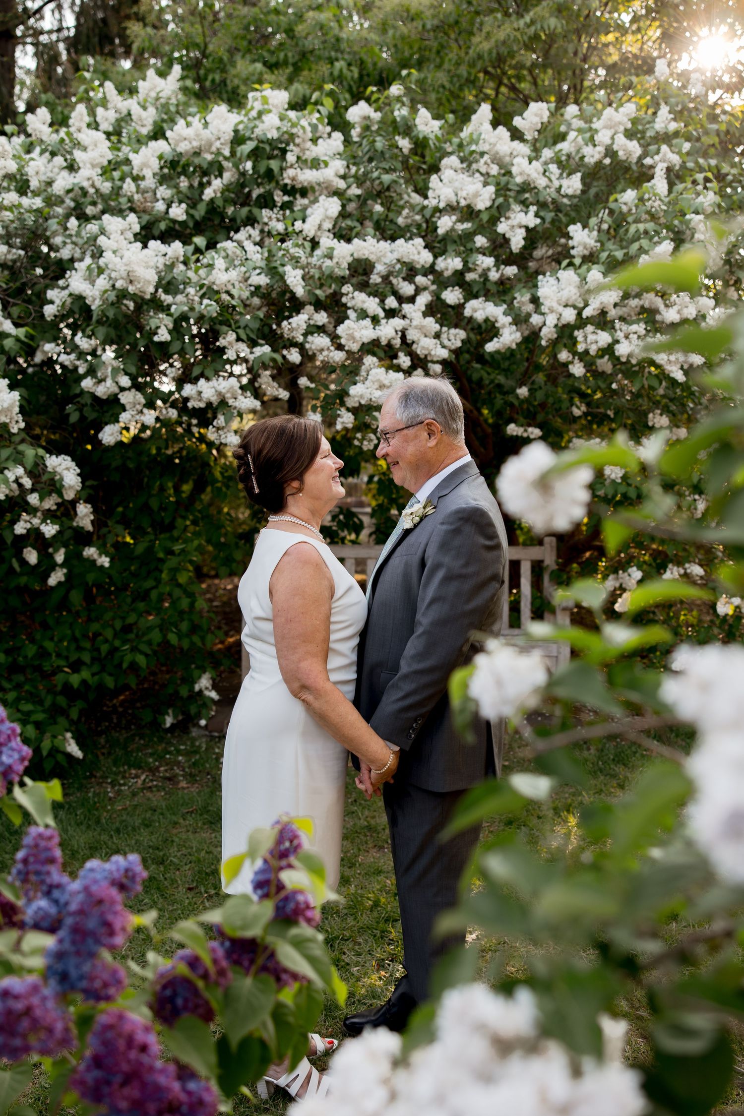 A romantic wedding moment captured among blooming white flowers in a garden setting. Twin Cities, Decorah Iowa wedding photography