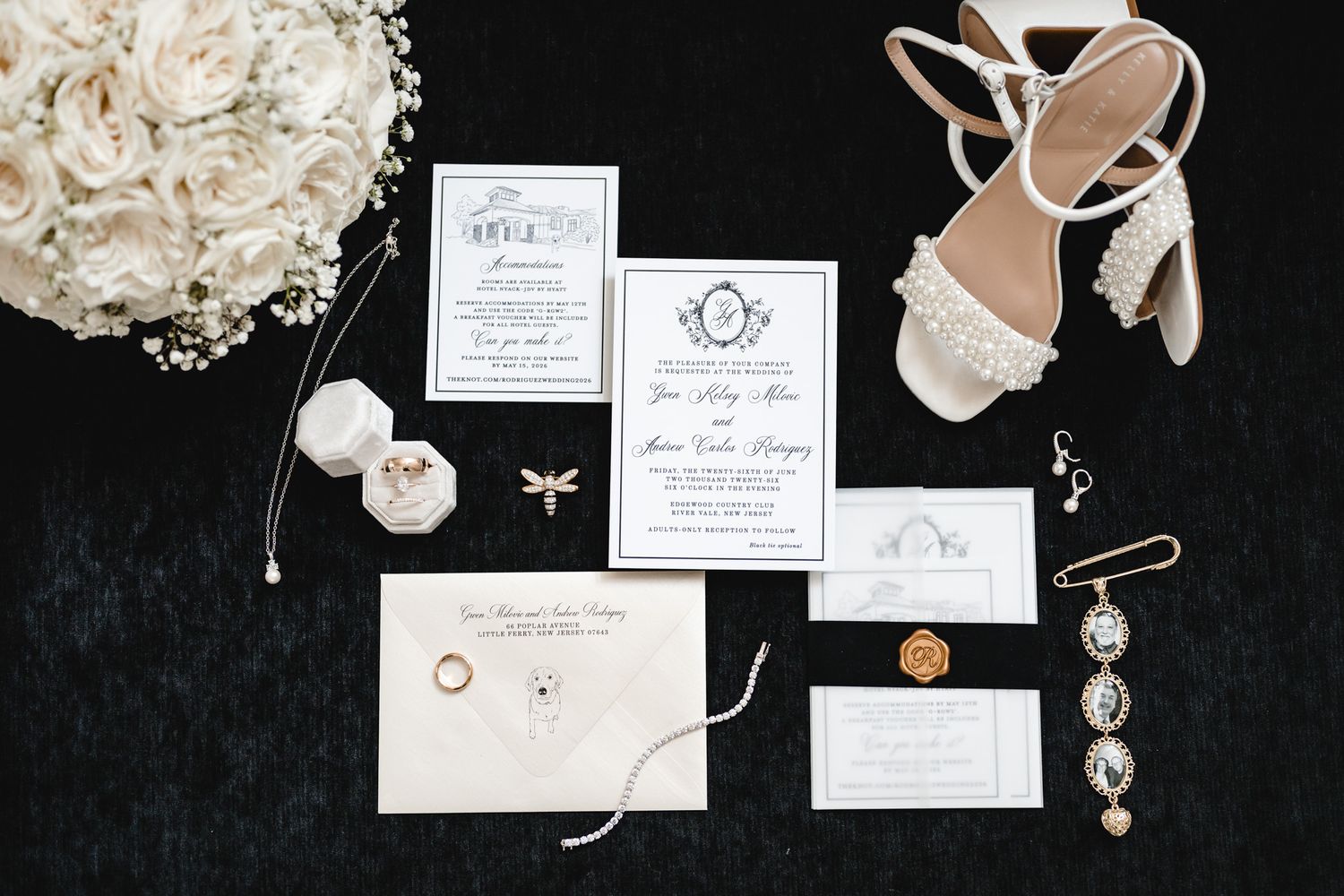 Elegant wedding flat lay with floral bouquet, pearl heels, gold rings, invitations, and delicate jewelry on dark velvet.