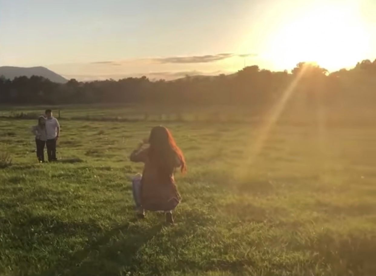 Behind the scenes of Ella Monroe Photography capturing an outdoor sibling portrait during a sunset family session in a North Georgia field