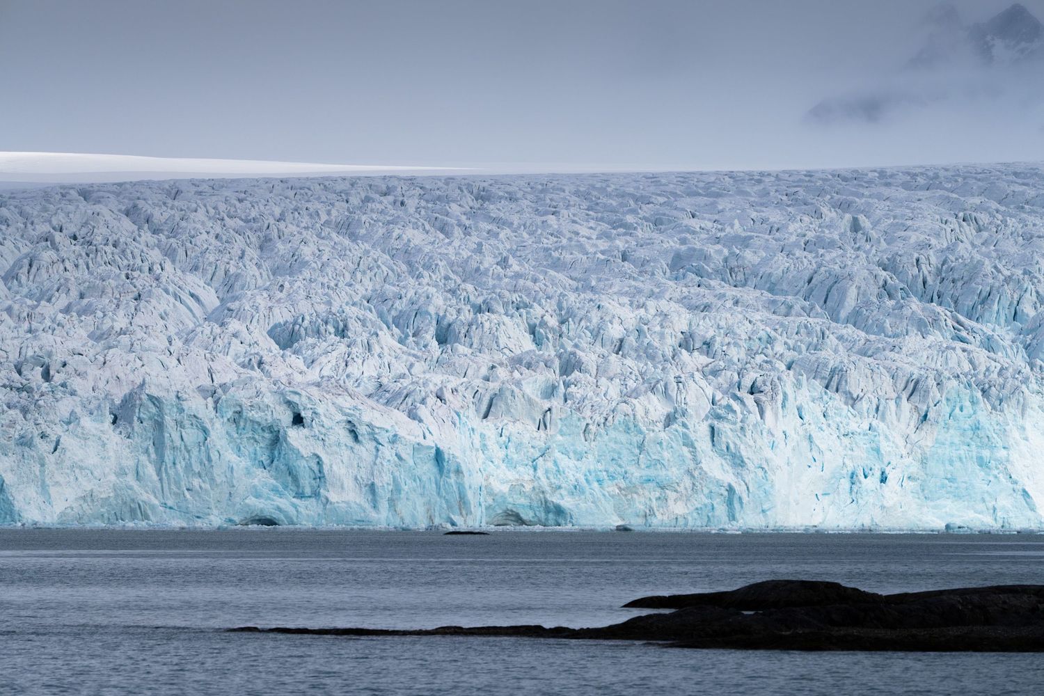 Séracs chaotiques d'un front glaciaire marin du Svalbard, îlot rocheux au premier plan