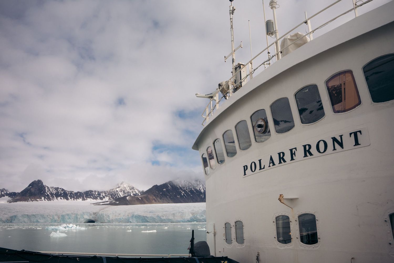 Proue du Polarfront et sa rangée de hublots face à des montagnes enneigées