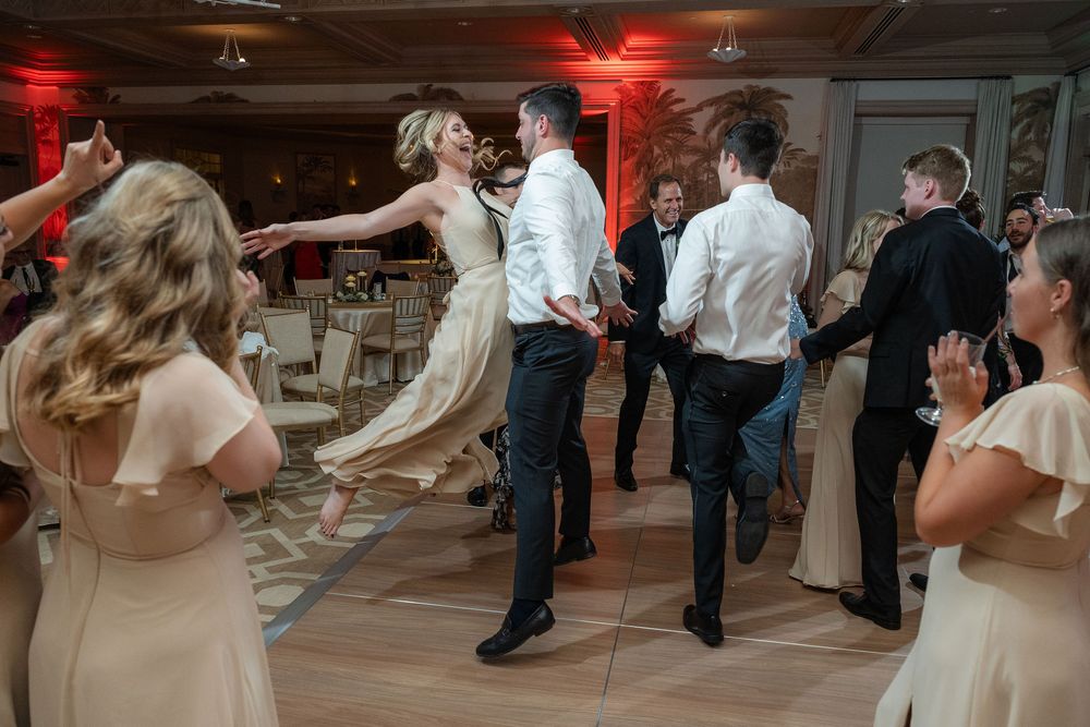 Bridesmaid leaping barefoot on the dance floor at a Lost Tree wedding in Palm Beach, FL