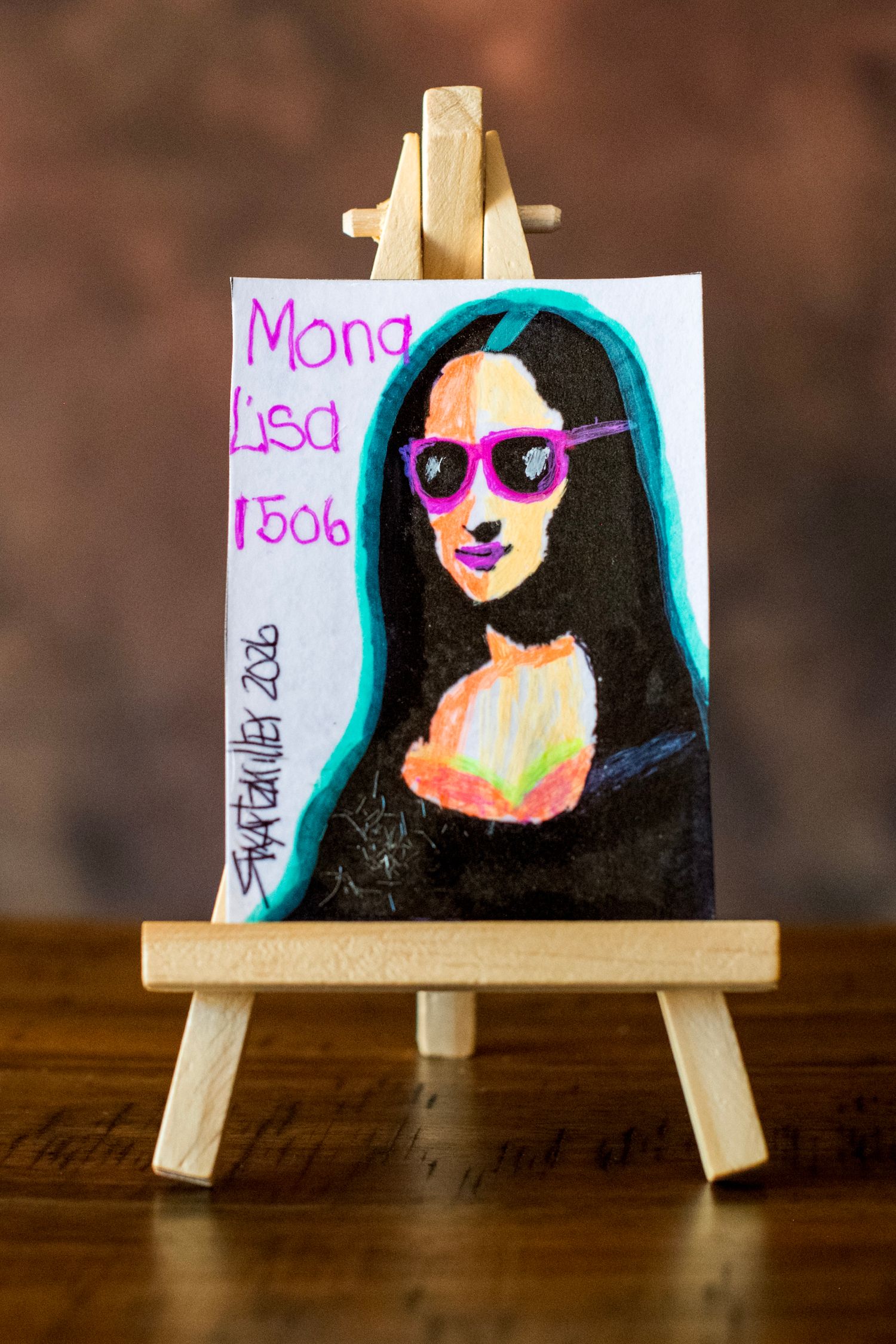 Mini easel painting of Mona Lisa 1506 with pink sunglasses and teal hair, colorful modern art reimagining.