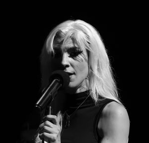 Black and white close-up of blonde female singer performing on stage with a microphone.