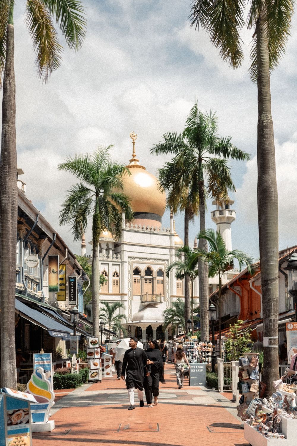 Visitors walk along Bussorah Street toward the iconic Sultan Mosque with its golden dome in Singapore's Kampong Glam district.