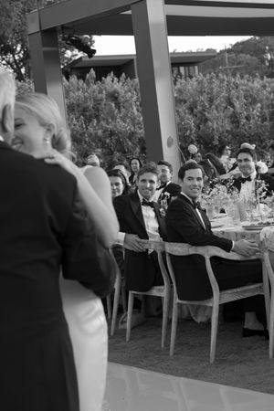 Wedding guests seated at tables watch a couple dancing during an outdoor evening reception celebration.